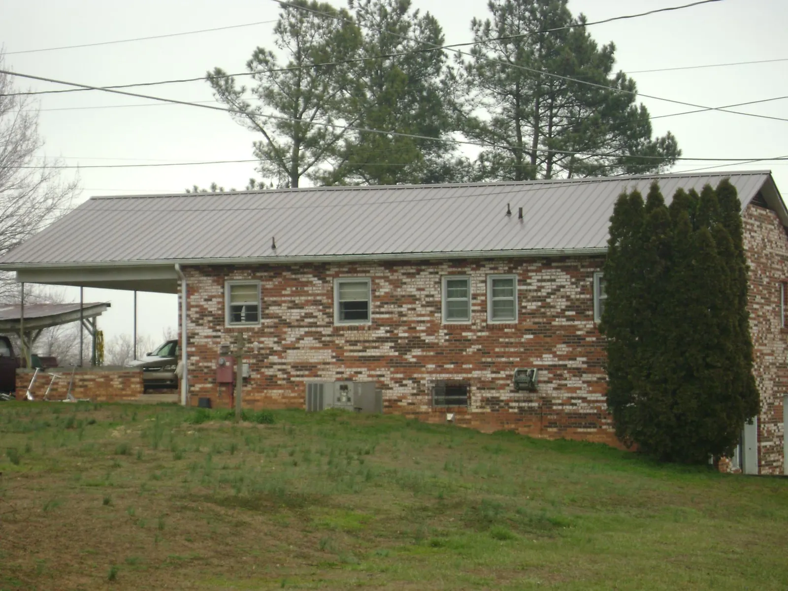 Gray metal roof on a brick split level home with a carport in Oakdale